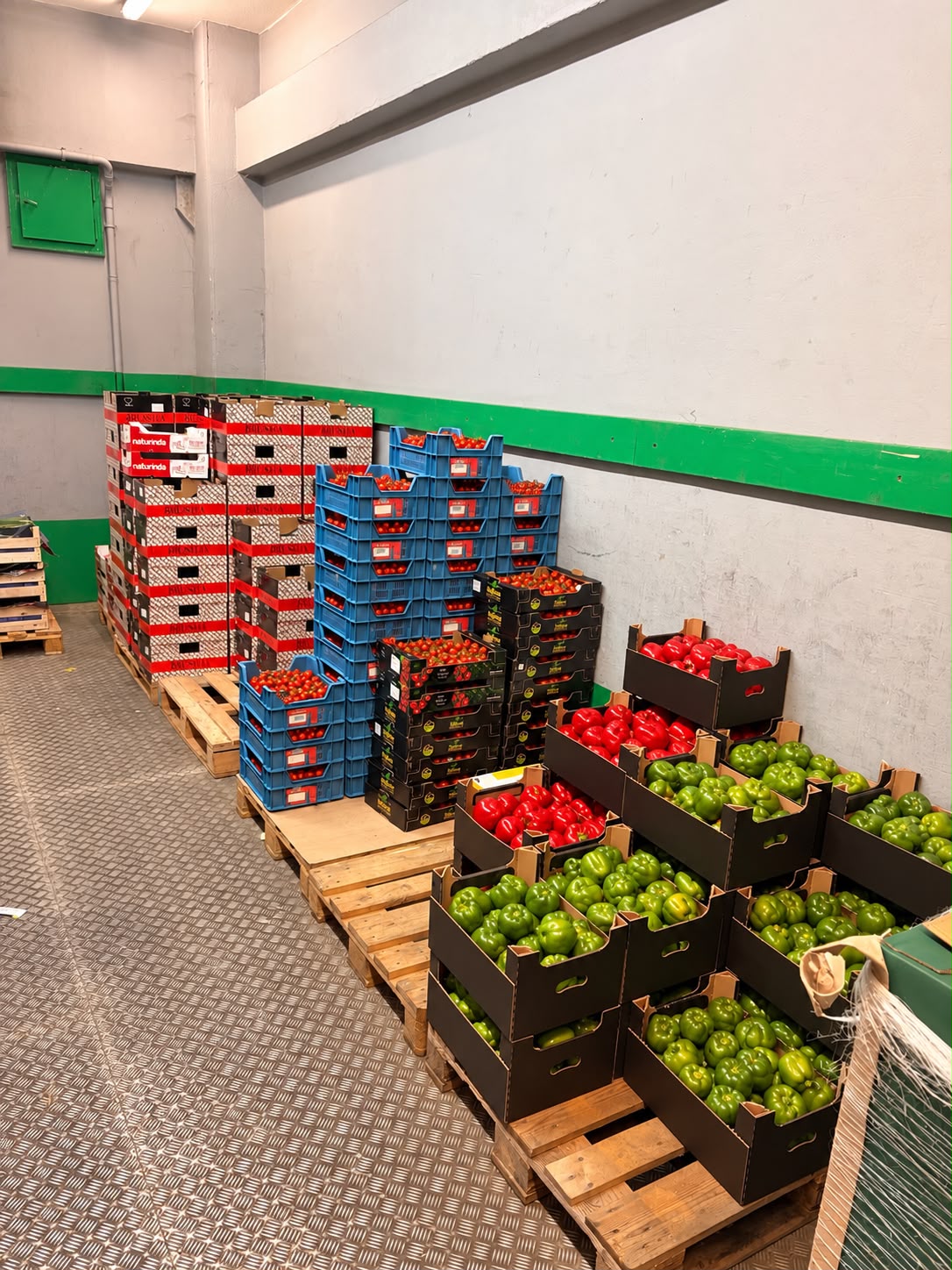 Kühlraum mit Kisten voll roter und grüner Paprika