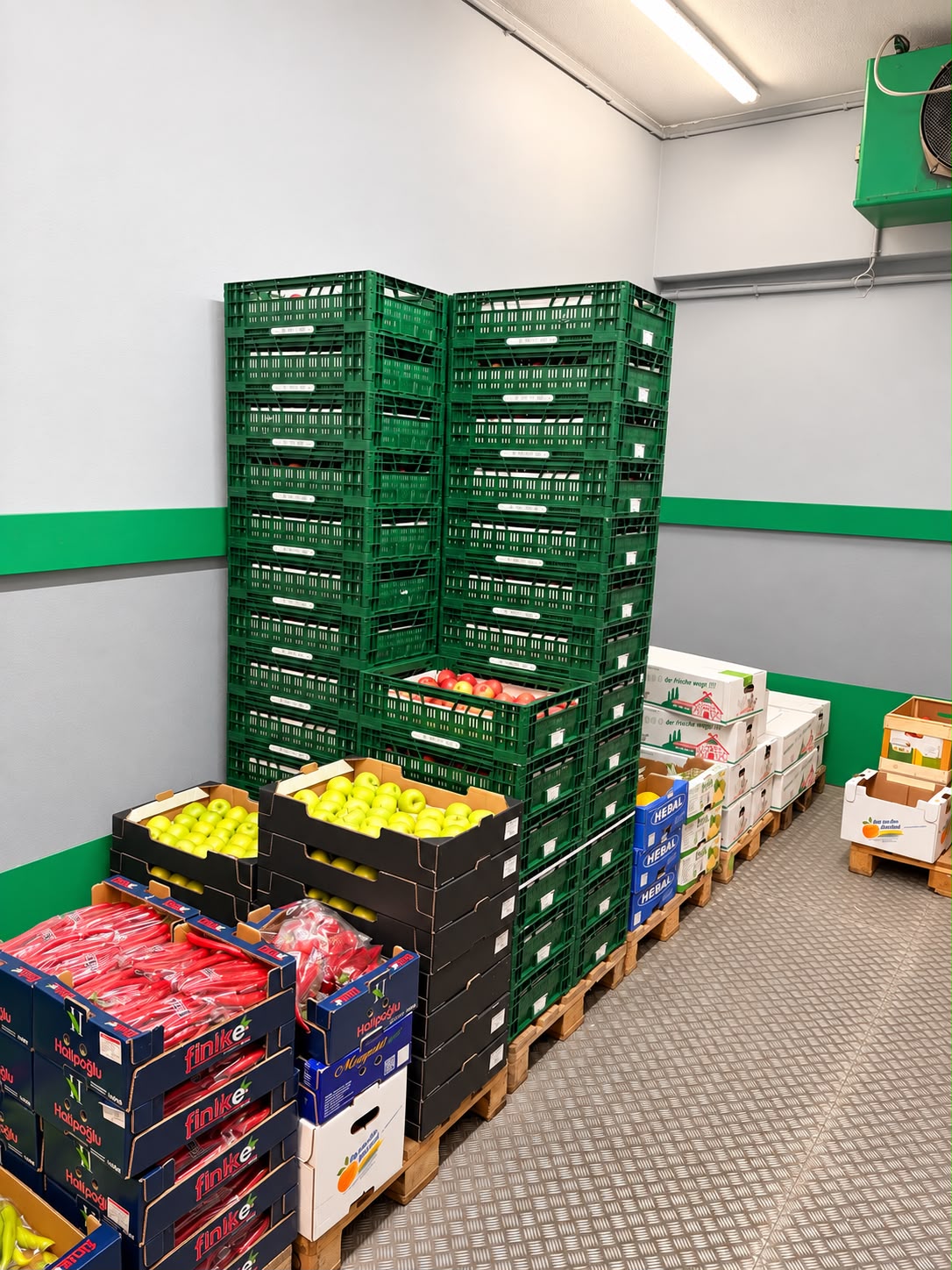 Kühlraum mit gestapelten grünen Kisten mit Obst